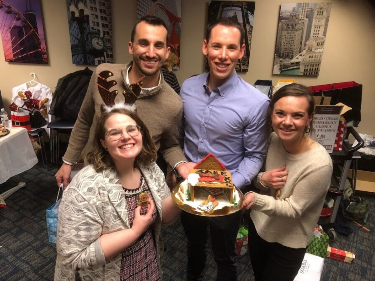 Group of four coworkers with gingerbread house