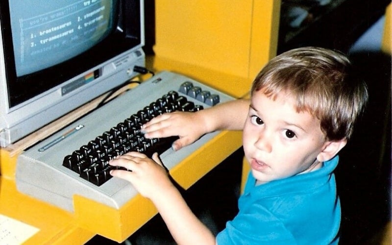1980s photo of a toddler typing at the computer.