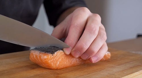A picture of a person cutting salmon